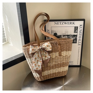 Detail of striped straw tote bag featuring floral silk scarf and brown leather handle