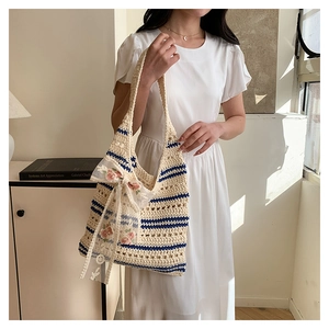 Detail of hand-woven tote bag with navy stripes and a white lace floral bow accent