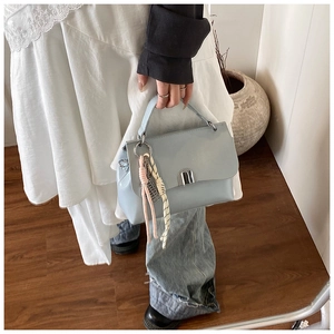 Detailed close-up of light blue soft leather handbag featuring silver twist lock and scarf charm