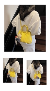 Gros plan d'un sac seau en cuir jaune avec grain texturé et breloque ours mignonne
