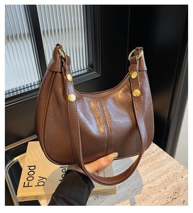 Detail of vintage brown crescent bag with retro lychee texture and golden metal buckle