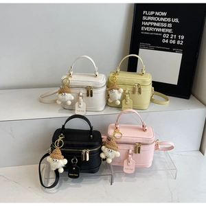 Close-up of small minimalist box bags in four colors with cute plush charms and gold hardware