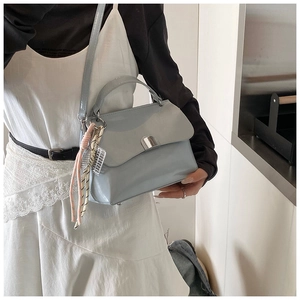 Close-up of light blue leather tote bag with silver buckle and silk scarf detail