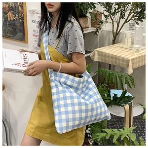 Detail showing the large capacity blue and white checkered canvas tote bag on a model