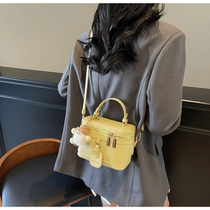 Detail of yellow box bag in pebbled leather with cute plush charm and gold-tone zippers