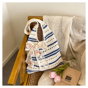 Detail of hand-woven tote bag in cream white with blue stripes and floral lace bow