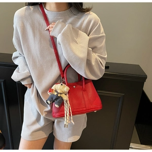 Détail du sac seau en cuir grainé rouge avec un adorable porte-clés ours en peluche