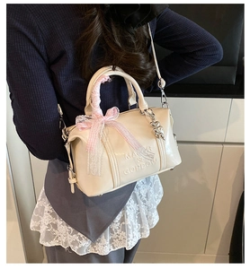 Detail of off-white Boston bag with pink lace bow and silver heart charm pendant
