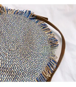 Detail of woven straw handbag showing blue fringe trim and spiral texture pattern