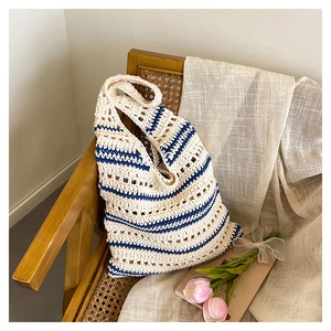 Detail of hand-woven crochet tote bag with blue and white stripes on a rustic chair