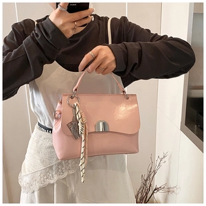 Detail of pink faux leather tote bag featuring silver metal clasp and striped silk scarf