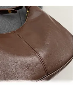 Macro detail of brown oil wax leather hobo bag showing fine texture and double stitching
