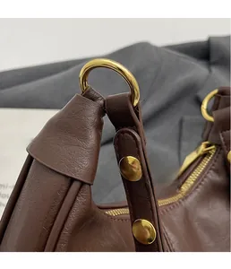 Close-up of brown leather handbag featuring golden metal ring buckle and fine craftsmanship