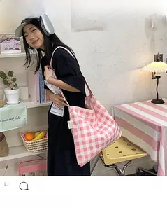 Lifestyle shot of pink checkered canvas tote bag with label detail on model's shoulder