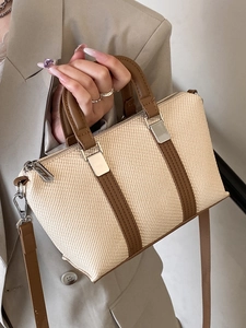 Minimalist woven tote bag with brown leather trim shown in a stylish handheld shot