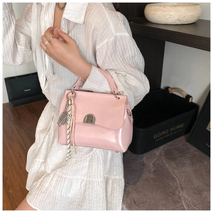 Pink faux leather tote bag with metallic twist lock and decorative woven lanyard detail
