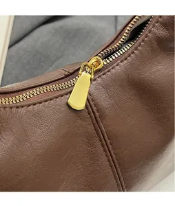 Close-up of golden metal zipper and荔枝 textured dark brown leather on the crossbody bag