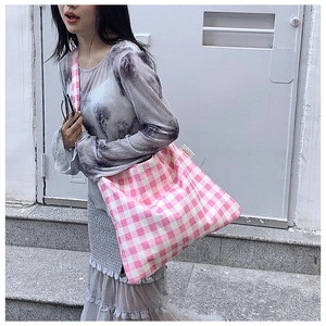 Detail of pink and white checkered canvas tote bag with side label on shoulder