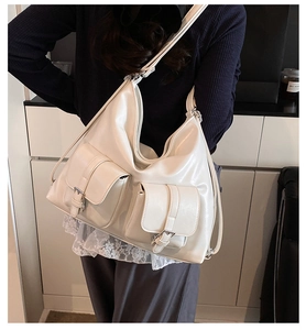 Close-up of creamy white large shoulder tote bag with double front buckled pockets