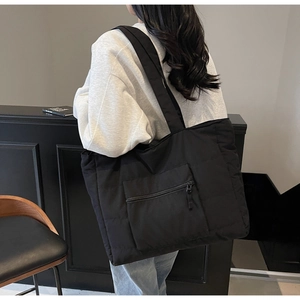 Vue détaillée du sac cabas matelassé noir avec poche latérale zippée et texture en nylon