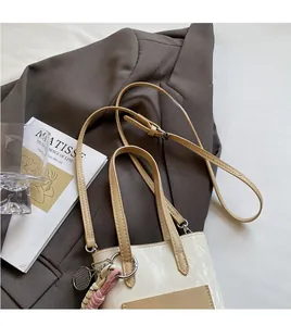 Detail of cream leather crossbody bag with metal ring charm on a dark brown blazer