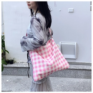 Outdoor shot of a pink gingham canvas tote bag with shoulder straps and side label