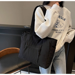 Détail du sac cabas matelassé noir avec poche zippée porté par un mannequin femme