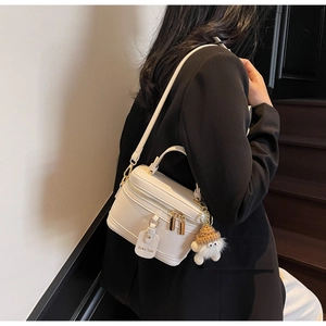Close-up of white box bag in pebble leather with a cute plush charm and gold hardware