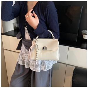 Detail of white glossy tote bag with silver metal lock and stylish pink tassel charm