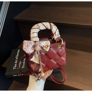 Detail of burgundy quilted mini handbag with pearl chain and silk scarf wrap on handle