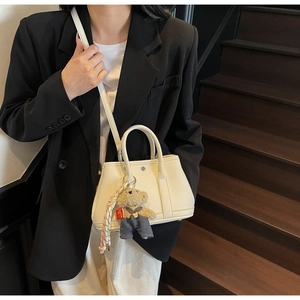 Détail du sac seau en cuir grainé blanc cassé avec boucles argentées et breloque ours