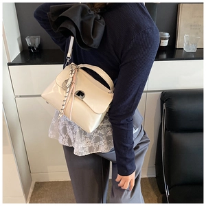 Detail of cream white leather tote bag featuring a silver buckle and woven strap ornament