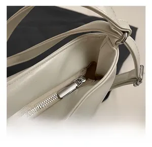 Detail of silver metal zipper and precise stitching on cream faux leather tote bag