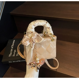 Detail of champagne mini handbag featuring quilted leather and silk scarf handle decor