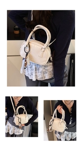 Detail view of cream mini bowling bag with bear charm and pearl strap on model