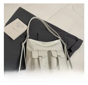 Detail view of cream faux leather tote bag showing two front pockets with silver buckles