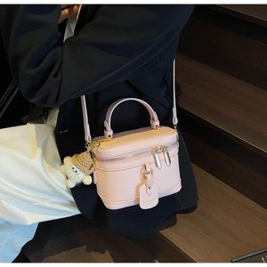 Detail of light pink box handbag with lychee texture leather and plush doll charm