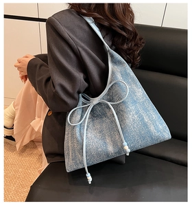 Dettaglio della borsa tote denim azzurra con finitura glitter, fiocchi e perline bianche