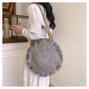 Detail of the woven round bag showing bohemian blue tassels and brown leather handle