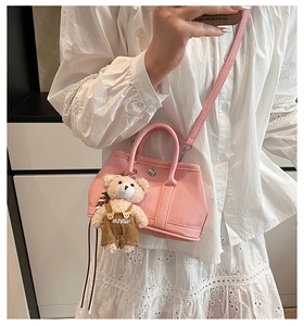 Selfie en el espejo de un mini bolso rosa de cuero granulado con un colgante de oso