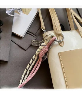 Detail of woven rope charm with metal abacus on a cream handbag for a stylish look