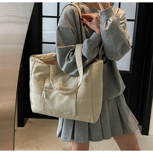 Détail du sac cabas matelassé beige minimaliste montrant la poche zippée et la bandoulière