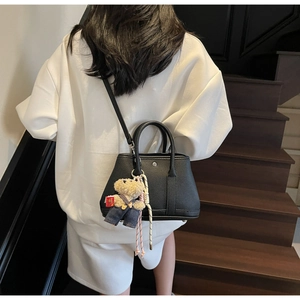 Détail du sac seau en cuir noir grainé avec boucle argentée et petit pendentif ours