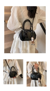 Macro detail of black patent leather mini bowling bag with cute cartoon charm and strap