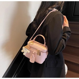 Detailed side view of pink pebbled leather box bag with cute plush doll and shoulder strap