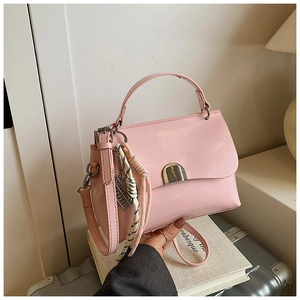 Close-up of pink tote bag with metal buckle, striped rope knot charm and shoulder strap