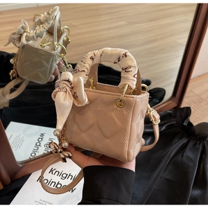 Detail of beige quilted mini handbag with gold ring handles and decorative silk scarf