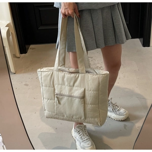 Vue détaillée du sac cabas matelassé beige avec poche zippée avant et larges bandoulières