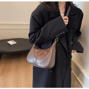 Retro brown leather crescent hobo bag shown being worn by a model in a minimal interior