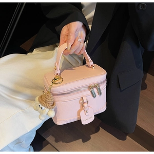 Pale pink lychee grain leather box bag featuring a cute plush pendant and gold zippers